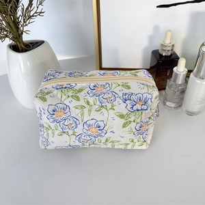Macro detail of quilted floral makeup bag with blue flowers and beige zipper closure