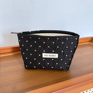 Close-up of black polka dot toiletry bag with textured fabric and May Rabbit label
