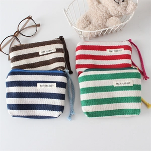 Detail of striped canvas mini wallets with metallic zippers and woven wrist straps