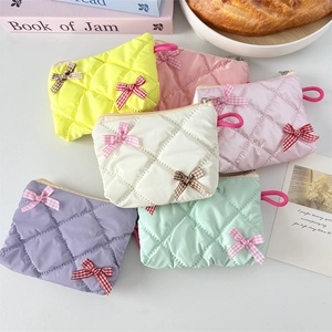 Detailed view of macaron colored quilted makeup bags with gingham ribbon bow accents