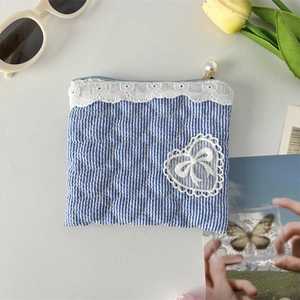 Detailed view of heart-quilted blue striped pouch with lace trim and pearl zipper
