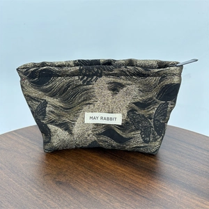Detail of gold butterfly fabric texture and brand label on a large makeup bag