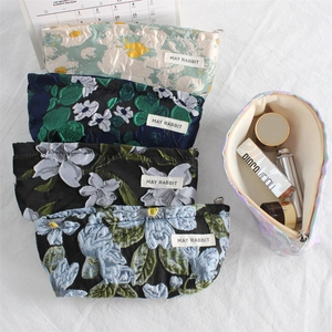 Detail of premium floral jacquard makeup bags with textured fabric and metal zippers