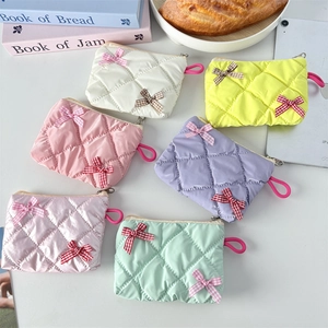 Detailed view of quilted mini cosmetic pouches with bow accents in six pastel colors