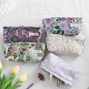 Detail of five mini canvas makeup bags with floral embroidery and gold metal zippers