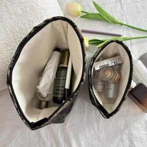 Detailed interior of large and small black butterfly makeup bags with gold leaf texture