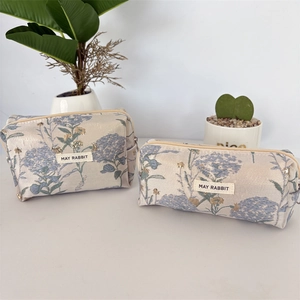 Détail de la texture jacquard florale sur l'ensemble de trousses à maquillage crème