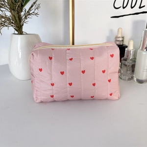 Detailed view of quilted pink makeup bag with red heart pattern and zipper closure