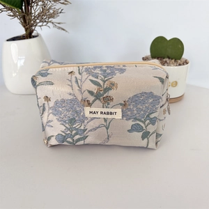 Détail de la trousse à maquillage en jacquard floral avec étiquette May Rabbit