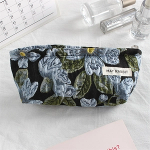 Detail of floral embroidery on a black canvas pouch with calendar and skincare accessories
