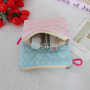 Detailed view of quilted heart cosmetic bags in pink and blue with convenient zipper pulls