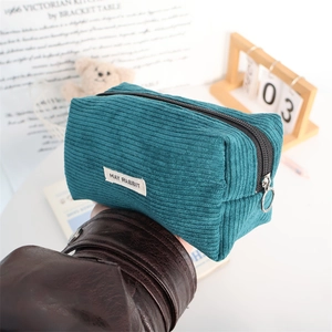 Detail of teal corduroy pouch showing textured fabric and silver ring zipper pull