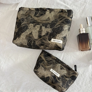 Detail of two-piece cosmetic bag set with golden butterfly jacquard and branded label