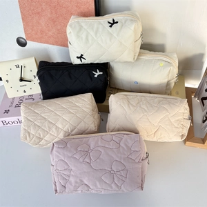 Quilted large capacity cosmetic bags in cream, black, and purple with zipper closure