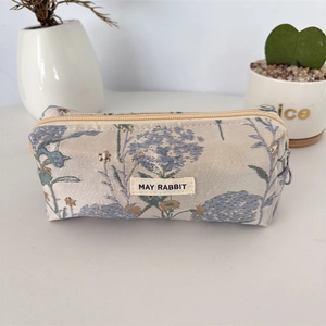 Détail du tissu jacquard à fleurs et de l'étiquette tissée sur la trousse à crayons