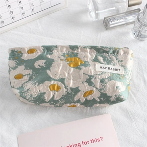 Close-up of floral jacquard fabric on a mini cosmetic bag with May Rabbit label