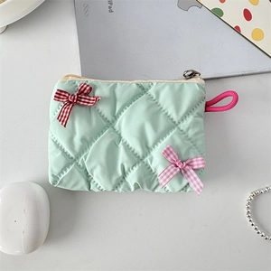 Detailed top view of a mint green quilted cosmetic bag with cute decorative bows
