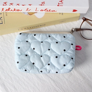 Close-up of heart-quilted light blue coin purse with black polka dots and zipper