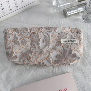 Detailed close-up of a floral jacquard makeup pouch with woven label and premium texture