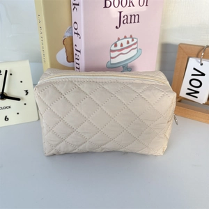 Detail of beige quilted makeup bag with diamond stitching and smooth zipper closure