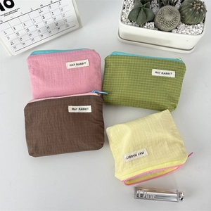 Close-up of four nylon grid makeup pouches with brand labels and colorful zippers