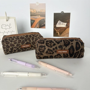 Detail of two leopard print pencil cases with brand logo on a cozy desk setting