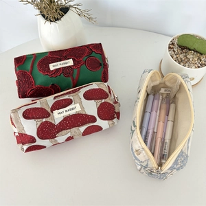 Trois trousses en jacquard avec motifs floraux et champignons et zips dorés