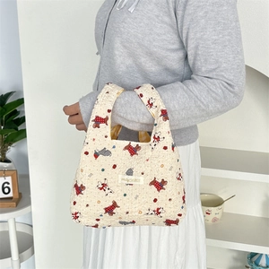 Detail of off-white quilted handbag with cute dog illustrations and brand label