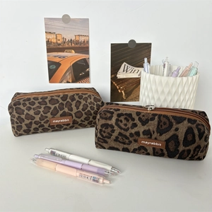 Close-up of leopard print suede pencil case with leather logo and zipper on the desk
