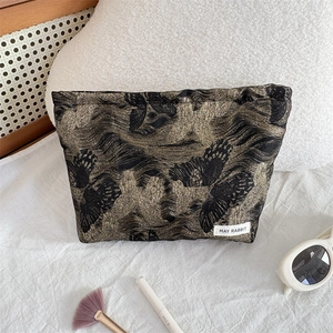 Detailed shot of black cosmetic bag with gold butterfly texture and makeup accessories