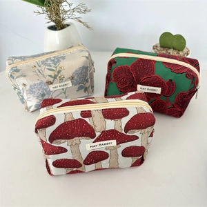 Détail des trousses avec motifs jacquard floraux et champignons et fermeture éclair