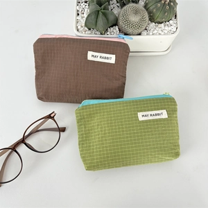 Detail of checkered nylon mini pouches with vibrant contrasting zippers and woven label