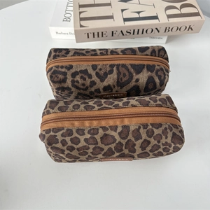 Detail of two leopard print suede pouches with zipper closure on a white surface