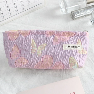 Detail of lavender pleated canvas makeup bag featuring embroidered butterfly and zipper