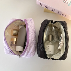 Detailed top view of large quilted cosmetic bags in purple and black with heart patterns