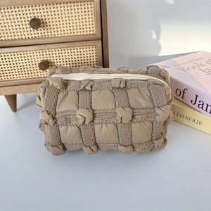 Close-up of quilted bubble texture and zipper on brown soft cosmetic wash bag