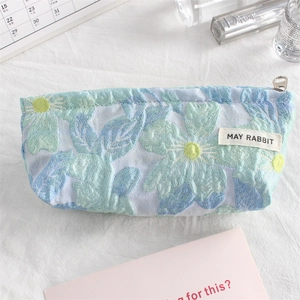 Detail of floral jacquard embroidery fabric with MAY RABBIT tag on a mini makeup bag
