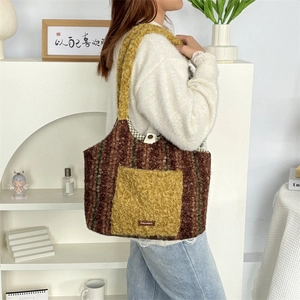 Winterliche Plüsch-Schultertasche mit bunten Streifen und weichem Material am Modell