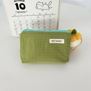 Detailed view of small green checkered nylon cosmetic pouch with blue zipper and logo label