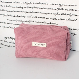 Detail of pink corduroy stationery bag with silver zipper pull and white fabric label