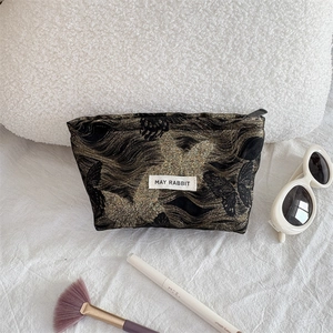 Detail of black jacquard makeup bag with golden butterfly pattern and MAY RABBIT tag