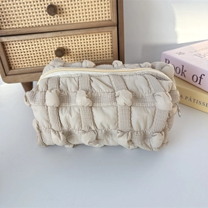 Detail of beige quilted bubble fabric pouch showing soft texture and zip closure