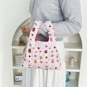 Detail of pink quilted tote bag featuring cute cartoon patterns and red checkered lining
