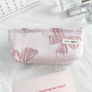 Macro shot of pink canvas cosmetic bag featuring detailed bow pattern embroidery