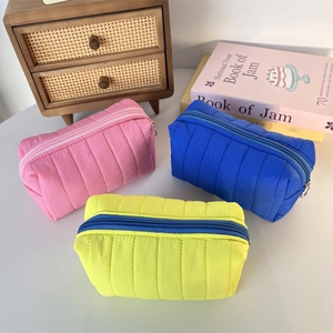 Three quilted makeup bags in pink, blue, and yellow with zipper and soft puffer texture