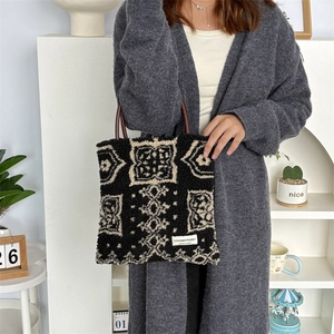 Detail of bohemian plush tote bag with black and white geometric patterns and leather handles