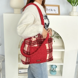 Detail der rot-beigen Plüschtasche mit Karomuster, Fleece-Riemen und kleinem Lederetikett