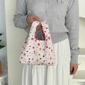 Detail of white bubble textured handbag with strawberry and puppy prints and plaid lining