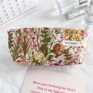 Close-up of floral embroidery on a compact canvas makeup bag with metallic zipper