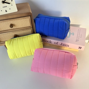Close-up of vibrant quilted cosmetic bags in blue, yellow and pink with metal zippers
